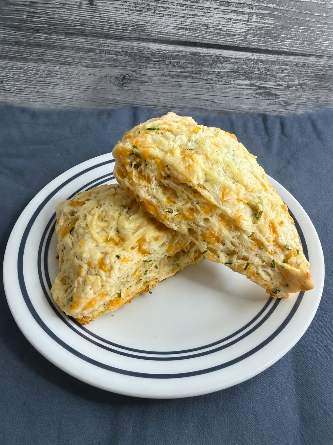 A cheddar chive scone split in half on a plate
